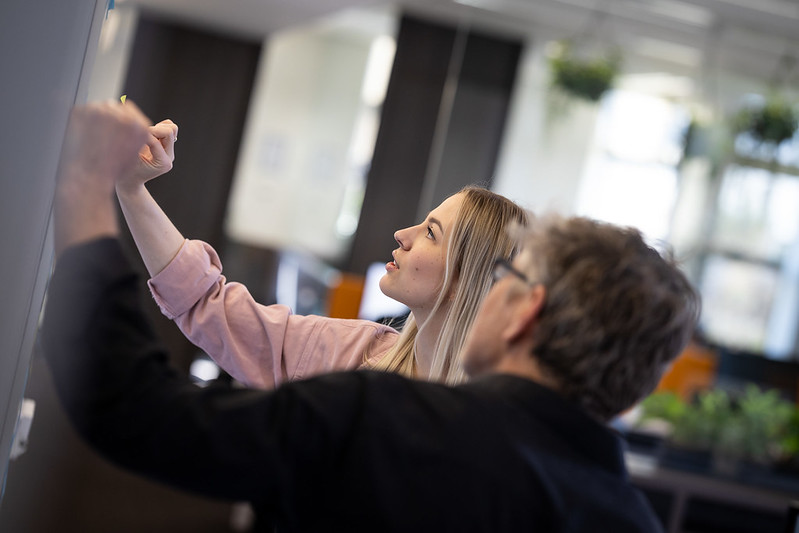 Two people writing and indicating a customer project